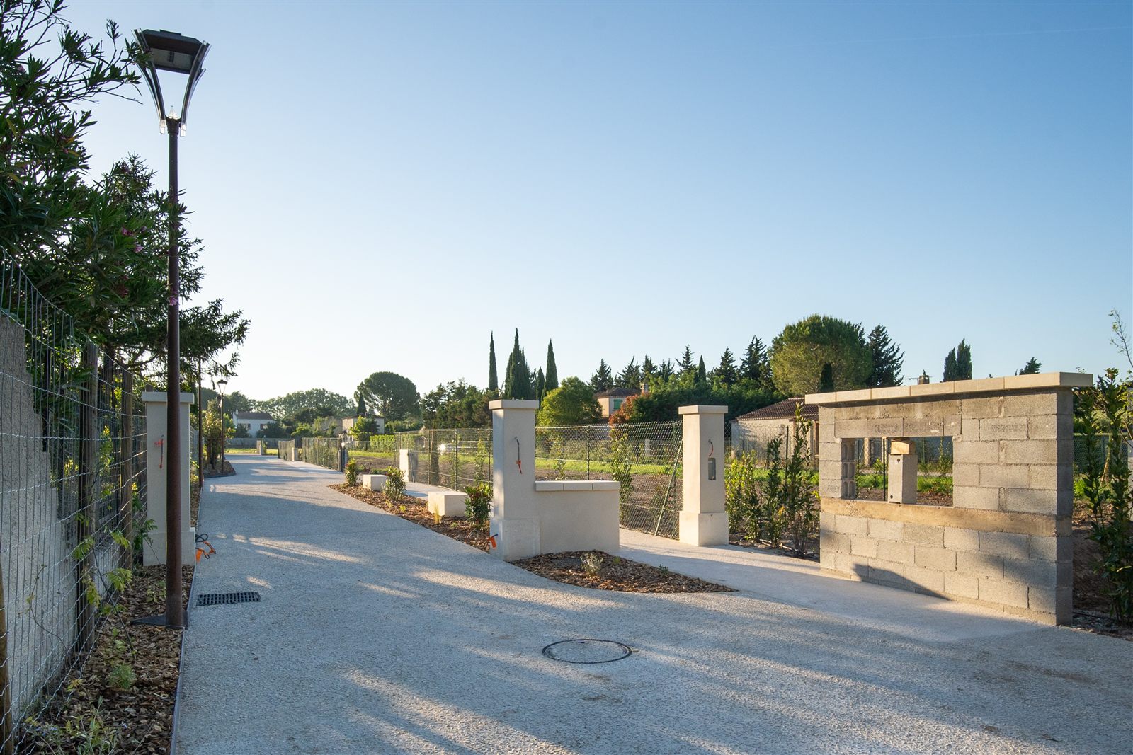 Entrée du lotissement — piliers en pierre, portail et plantations, Fontvieille
